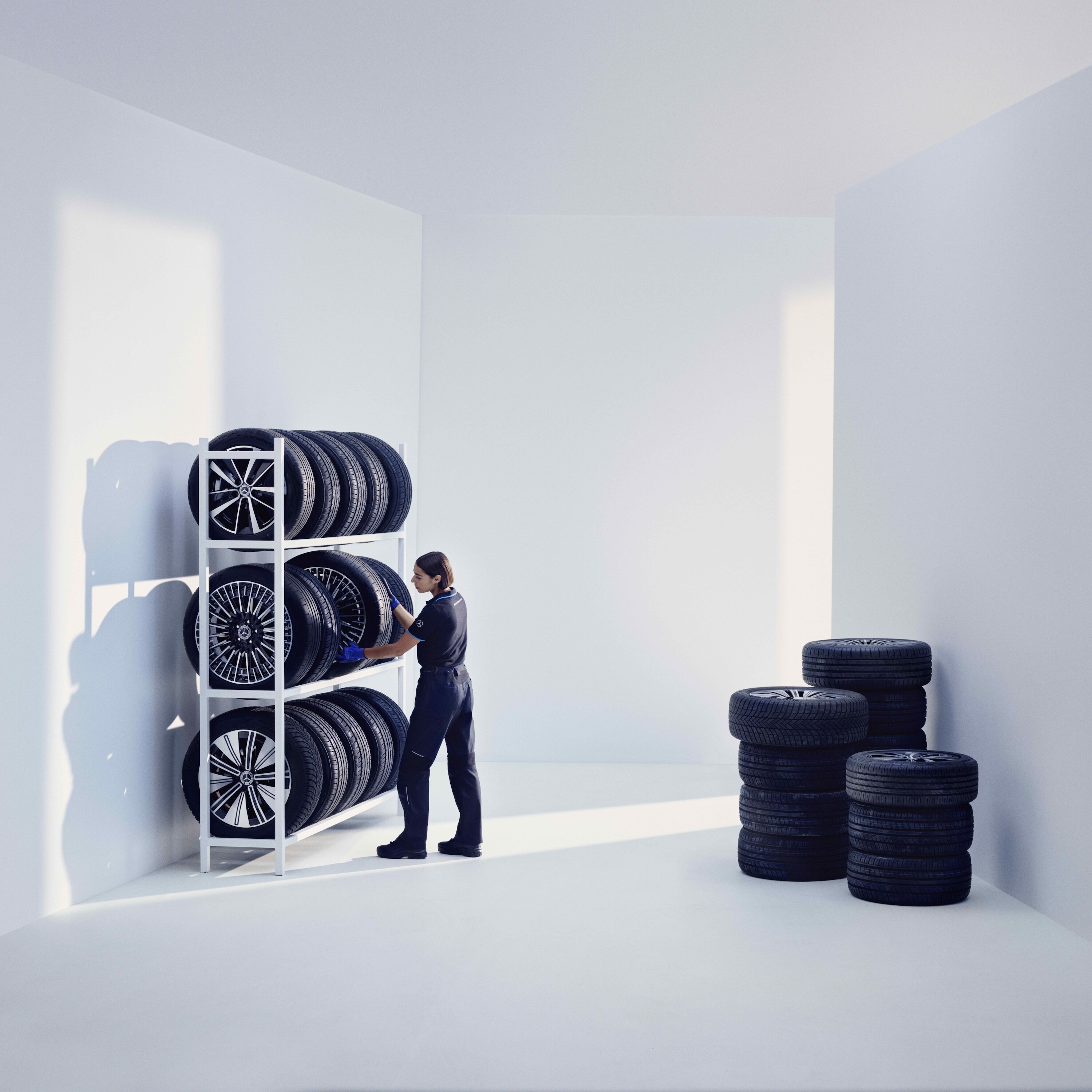 A Mercedes-Benz technician stores Mercedes-Benz Original tires on a shelf.