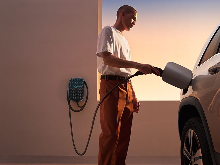 The EQB from Mercedes-EQ with the Mercedes-Benz Wallbox. A man is in the process of charging the EQB.