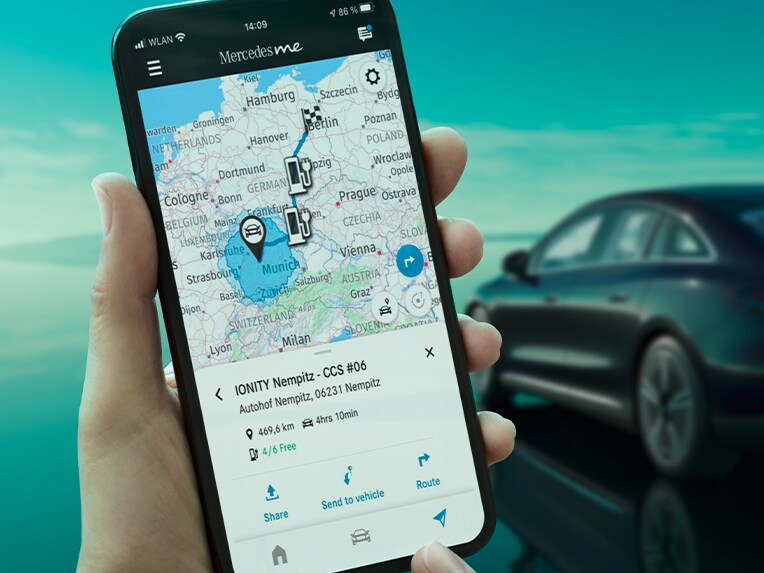 The ECO Coach app on a smartphone, and in the background the EQE Saloon charging at a wallbox.