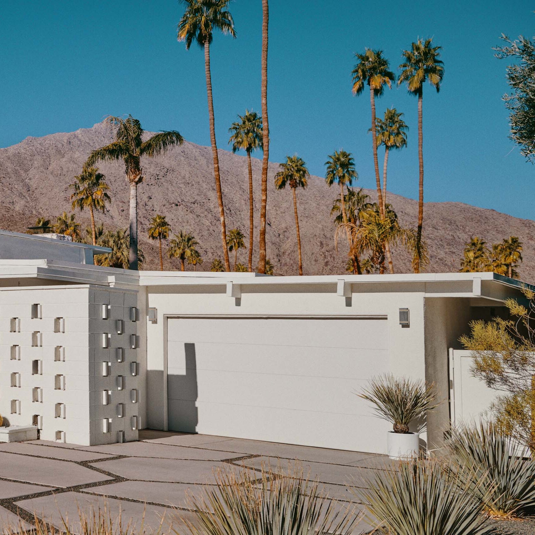 A suburban white architectural house with a driveway and a garage.