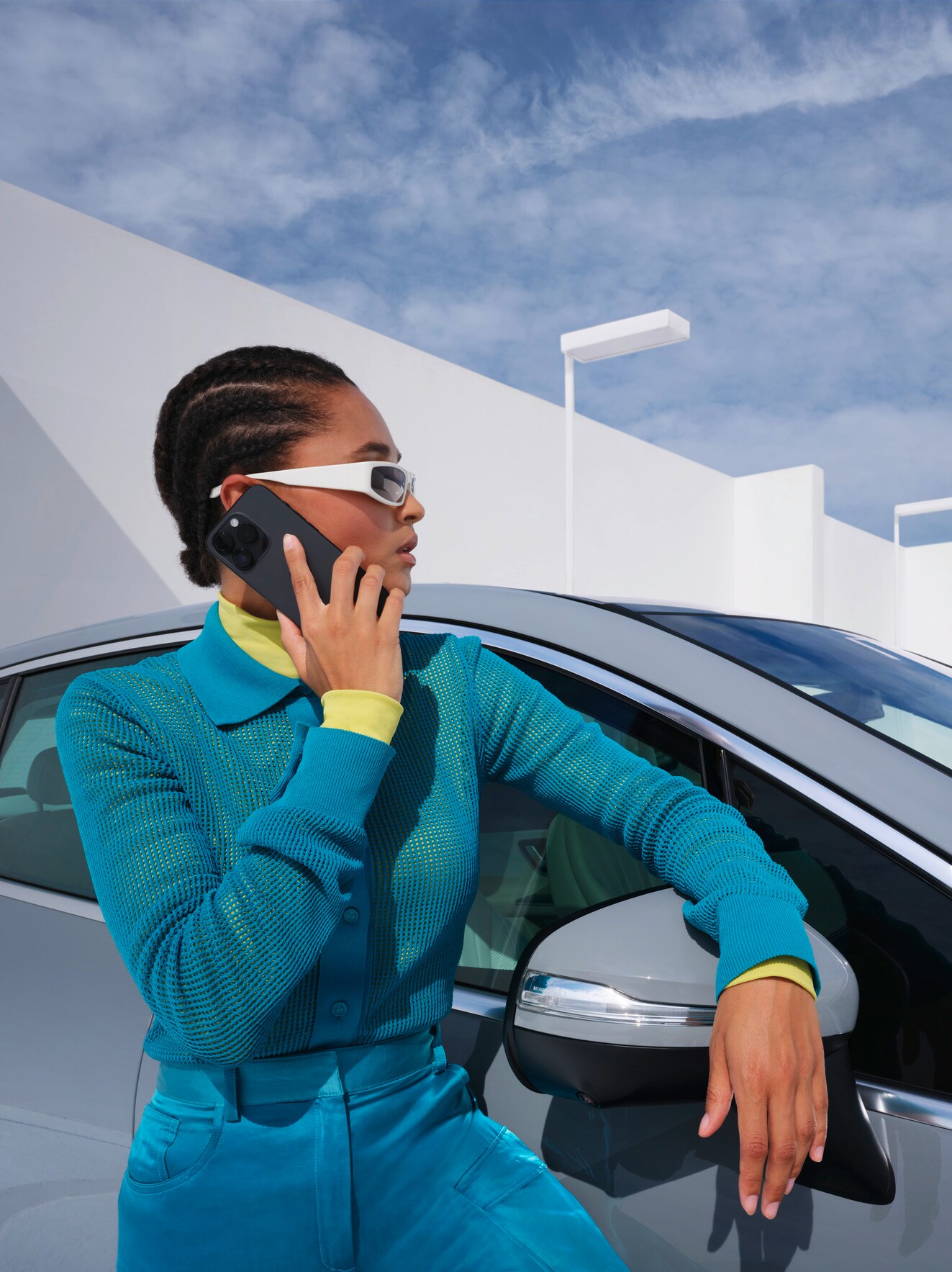 Woman leaning on her Mercedes-Benz on the phone. 