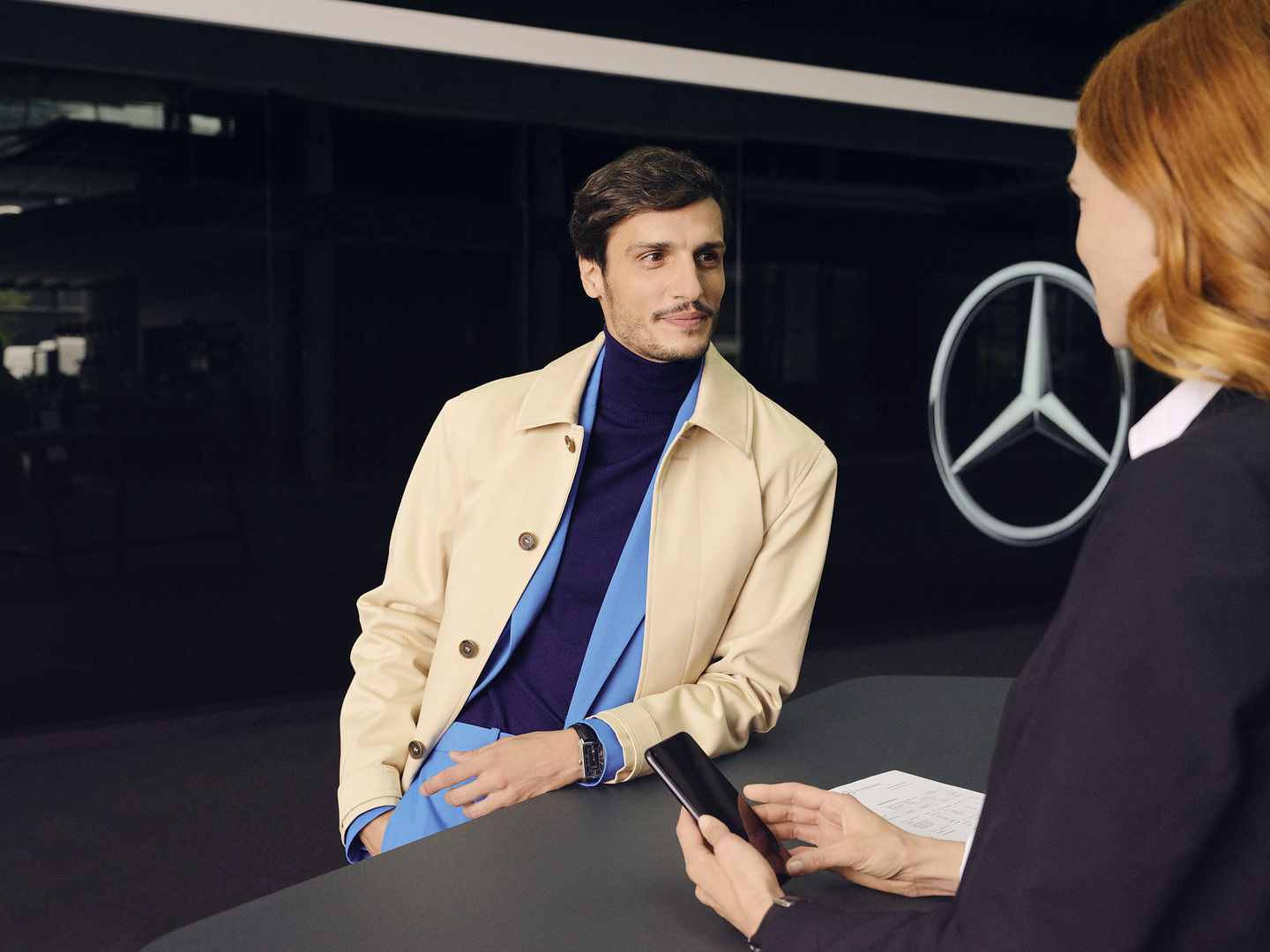 Mercedes-Benz Recall | Mercedes-Benz A customer leaning at the counter turns expectantly to face a Mercedes-Benz employee.