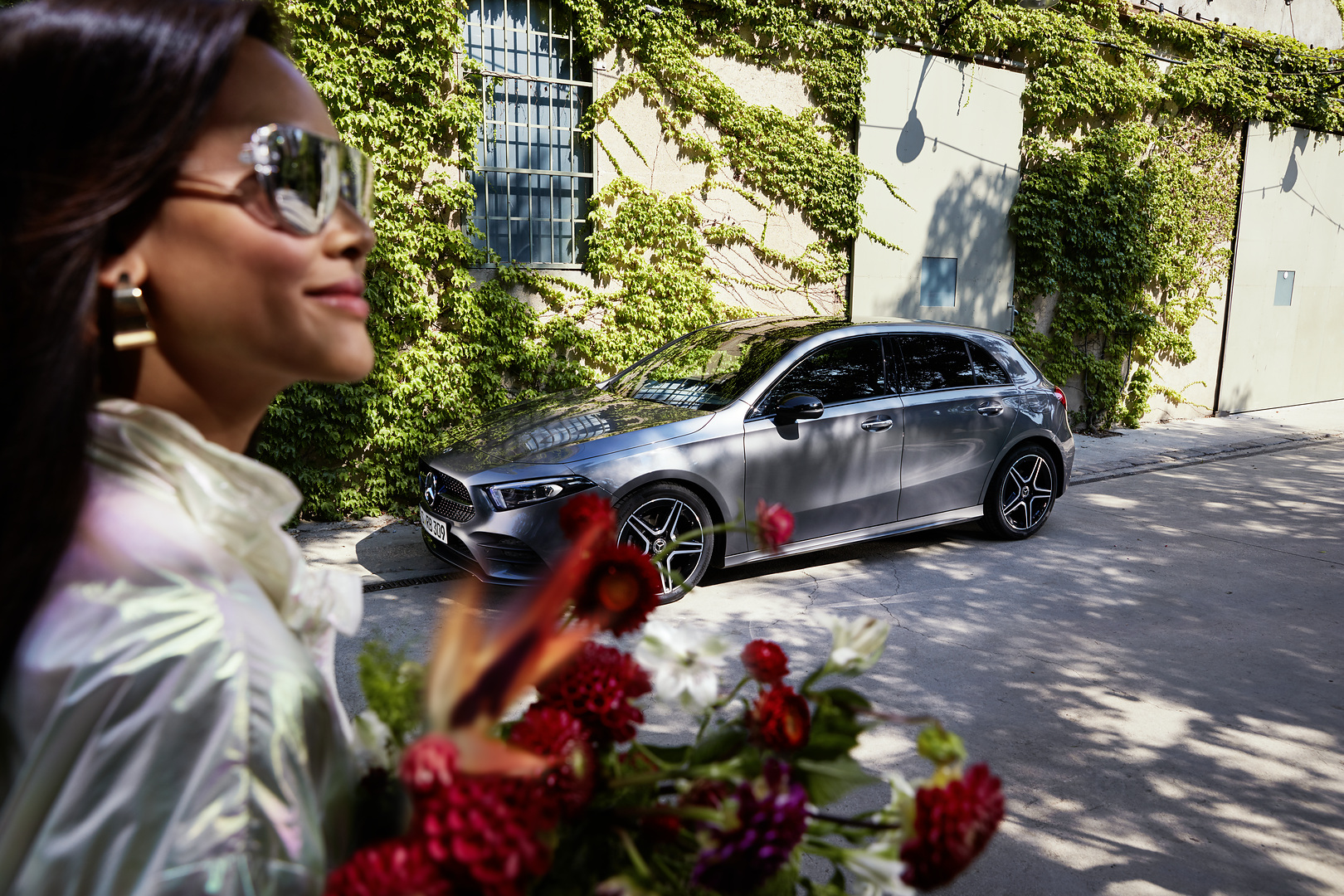 As reassuring as Mercedes ServiceCare. | Mercedes-Benz A woman holding flowers and looking relaxed as she approaches her serviced Mercedes.