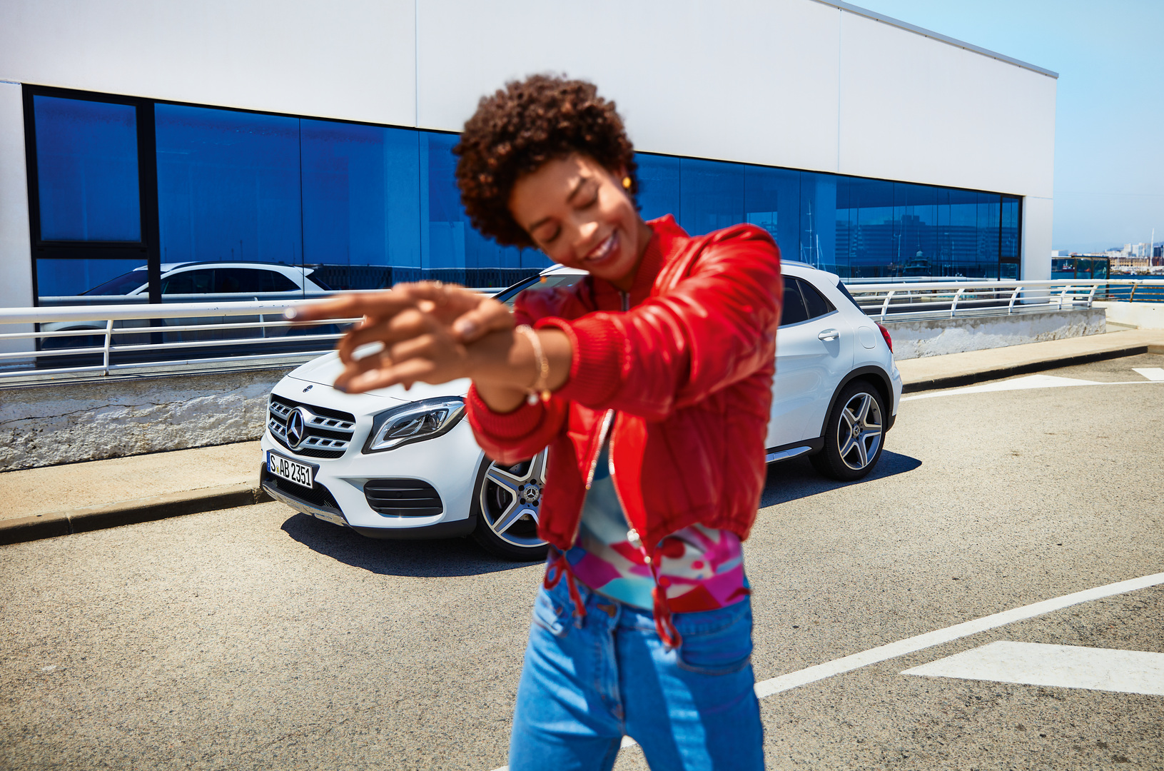 A woman standing on a street in front of her white Mercedes. | Mercedes-Benz Mercedes-Benz CompleteCare leaves time for the important things in life...