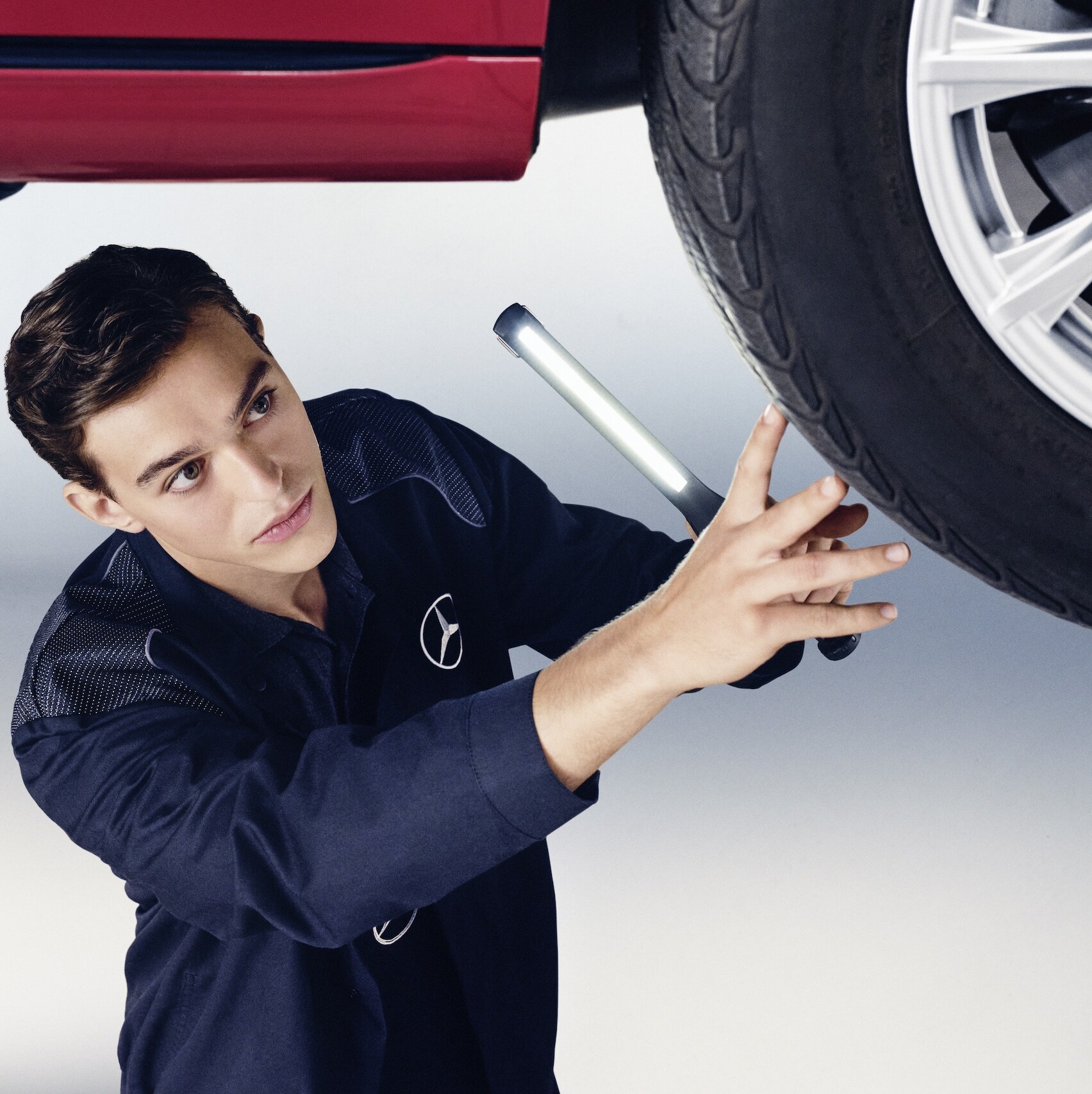 A Mercedes-Benz mechanic examines the wheel of a Mercedes-Benz.