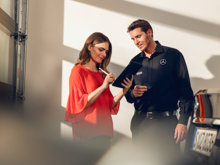 GenuineParts v. Non-genuine parts A woman signs a document on a tablet in the workshop.