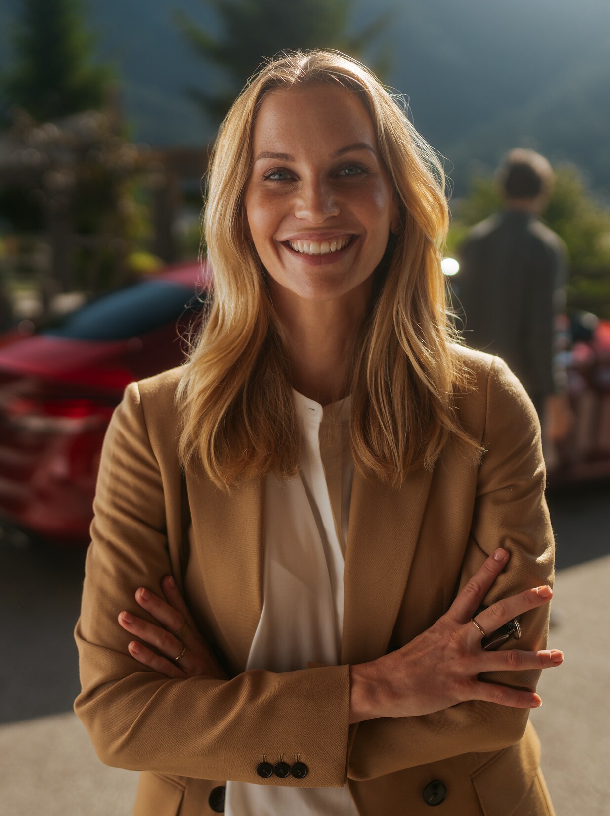 A woman, standing in front of her Mercedes and looking in a good mood.